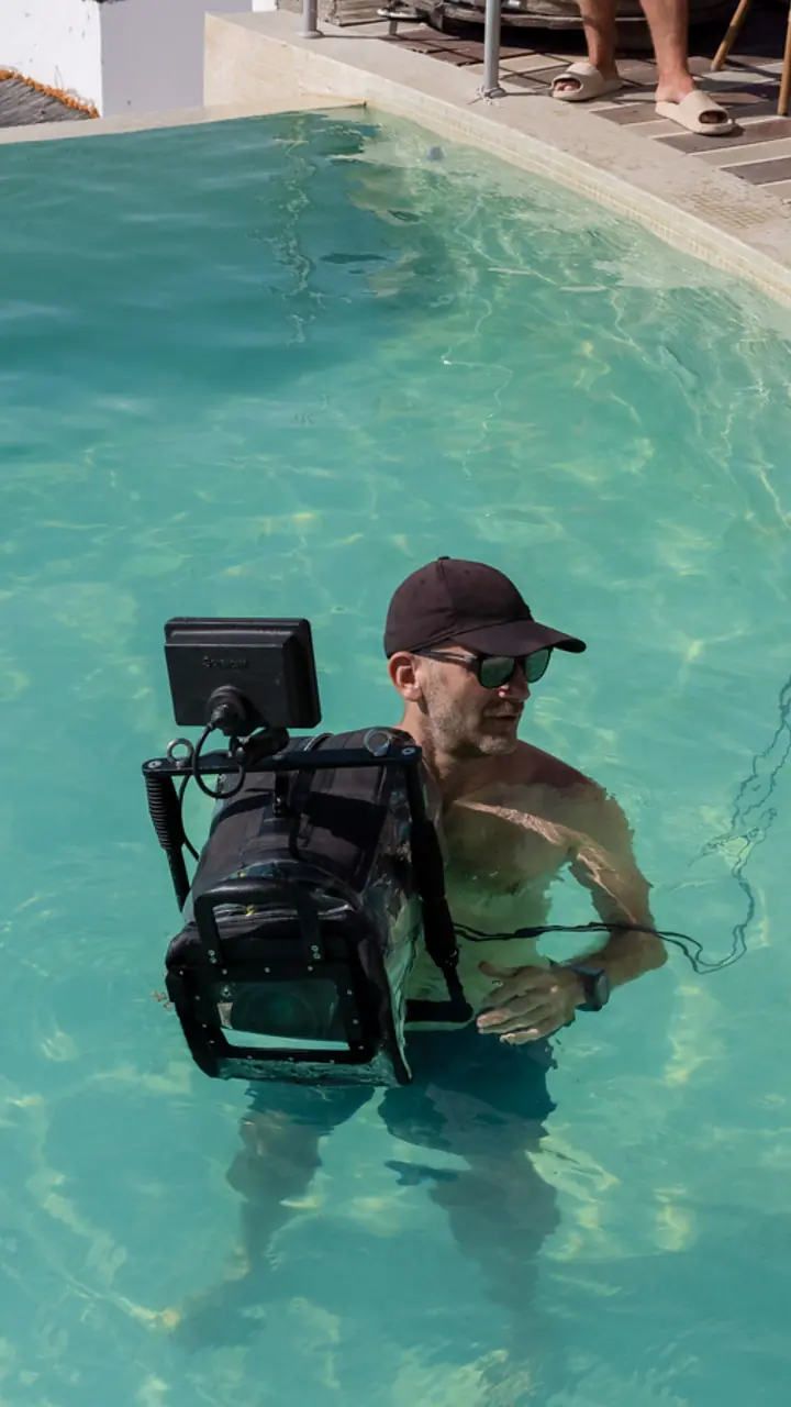 Operator cu aparatul de filmat, intrat în piscină până la brâu